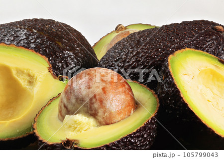 Closeup detail of avocado - Hass / Bilse variety - pit visible in halved pears Closeup detail of avocado - Hass / Bilse variety - pit visible in halved pears 105799043