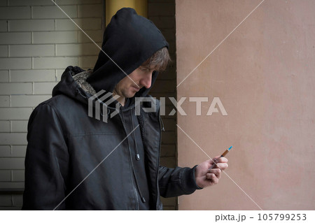 Addict with a syringe in his hand on the street. Addiction concept. Lifestyle 105799253