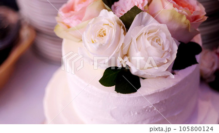 close-up, snow-white cream three-story cake, decorated with roses. traditional wedding cake, wedding traditions, accessories. 105800124