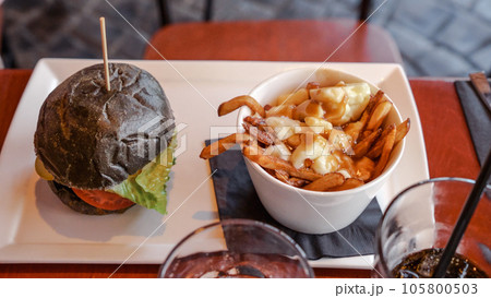 Vegan burger with French fries. Burger with plant based meat cheese. Lunch is on the table. Close-up of a hamburger with cheese on a board.Classic burger. Food day. Vegan burger with French fries. Burger with plant based meat cheese. Lunch is on the table. Close-up of a hamburger with cheese on a board.Classic burger. Food day. 105800503