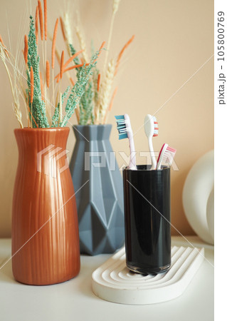 colorful toothbrushes in white mug against a wall  105800769