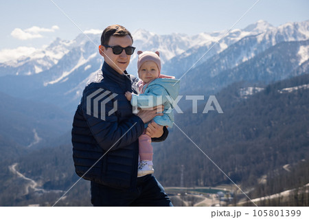 Father holds toddler daughter against snowy mountains peaks Father holds toddler daughter against snowy mountains peaks 105801399