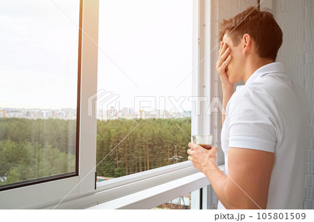 Man drinks cup of coffee on balcony overlooking forest 105801509