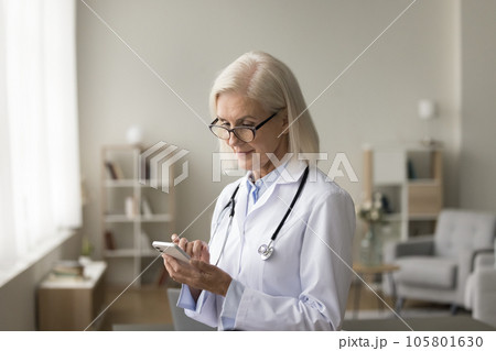 Mature doctor checking appointment schedule on professional app 105801630