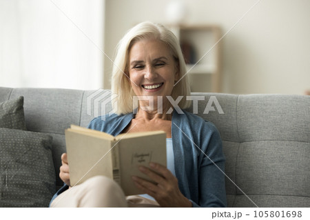 Happy blonde senior retired woman reading paper book 105801698