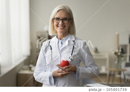 Happy senior doctor woman holding red heart shape at chest 105801739