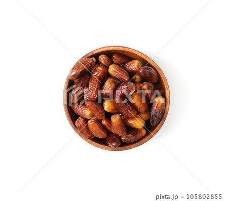 Wooden bowl with dried dates isolated on a white background. Dates closeup. Top view, flat lay. Wooden bowl with dried dates isolated on a white background. Dates closeup. Top view, flat lay. 105802855