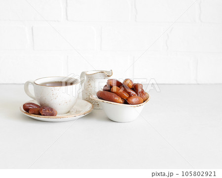 Dried dates and tea drink on white background with a copy space. Traditional Oriental food. Natural sweets. Healthy breakfast. Dried dates and tea drink on white background with a copy space. Traditional Oriental food. Natural sweets. Healthy breakfast. 105802921