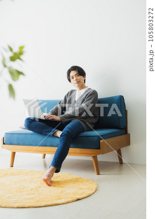 リビングのソファに座ってパソコンを使う若い男性 105803272