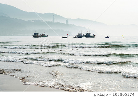 Boats floating near the beach besides the mountain in the brilliant dawn Boats floating near the beach besides the mountain in the brilliant dawn 105805374