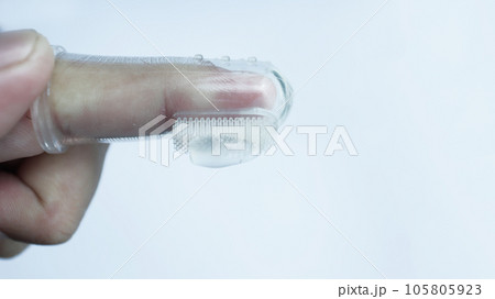 A hand wearing baby tooth brush or infant tooth brush, helping the first teeth clean isolated on white some negative space. 105805923