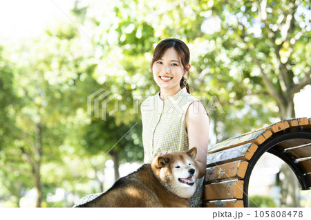 公園のベンチで休憩する若い女性と柴犬 105808478