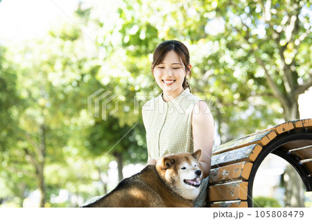 公園のベンチで休憩する若い女性と柴犬 105808479