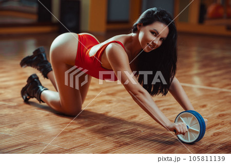 Young fitness woman training with abdominal wheel Young fitness woman training with abdominal wheel 105811139