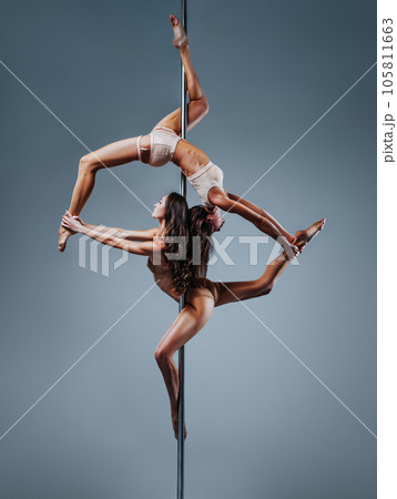 Two slim pole dance women on white wall background 105811663