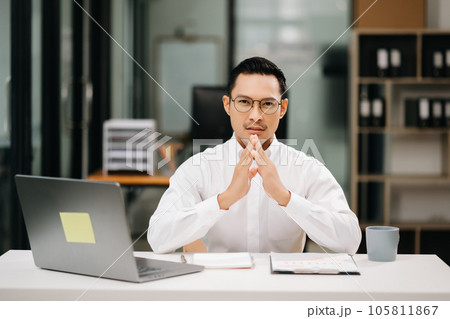 Confident Asian man with a smile standing holding notepad and tablet at the office. 105811867