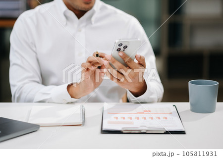 Asian business man documents on office desk with laptop and smart phone and graph business diagram and man working Asian business man documents on office desk with laptop and smart phone and graph business diagram and man working 105811931
