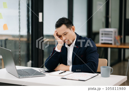 Overworked young Asian businessman office worker suffering from neck pain after had a long day at her office desk. office syndrome concept. 105811980