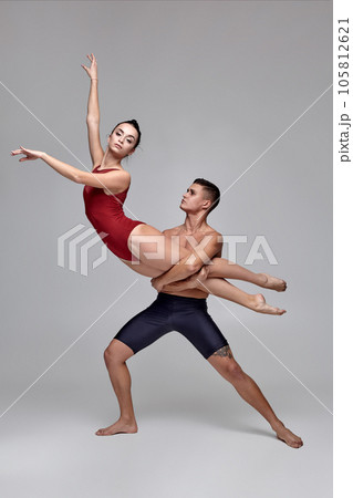The couple of an athletic modern ballet dancers are posing against a gray studio background. The couple of an athletic modern ballet dancers are posing against a gray studio background. 105812621