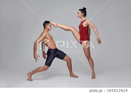 The couple of an athletic modern ballet dancers are posing against a gray studio background. The couple of an athletic modern ballet dancers are posing against a gray studio background. 105812624