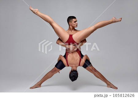 The couple of an athletic modern ballet dancers are posing against a gray studio background. 105812626