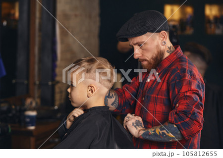 Caucasian boy getting haircut in barbershop indoor Caucasian boy getting haircut in barbershop indoor 105812655