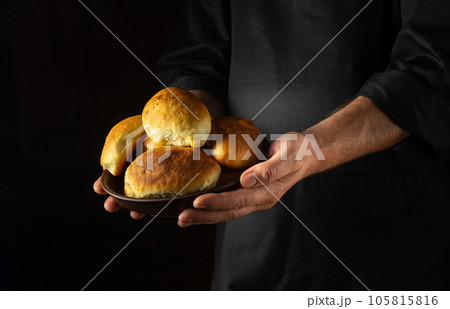 Patties or pies with dill on a plate in the hands of a baker. Ukrainian national dish. Black space for prescription Patties or pies with dill on a plate in the hands of a baker. Ukrainian national dish. Black space for prescription 105815816