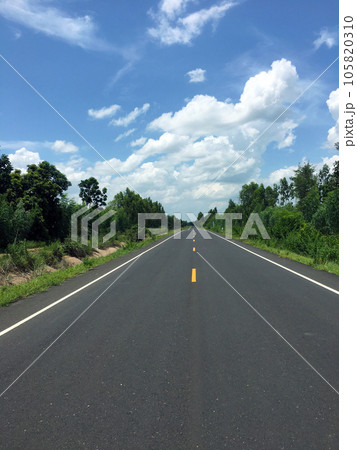 Image of new paved road in the daytime in the countryside painted yellow dividing line with trees, grass along the road, sky with white clouds Image of new paved road in the daytime in the countryside painted yellow dividing line with trees, grass along the road, sky with white clouds 105820310