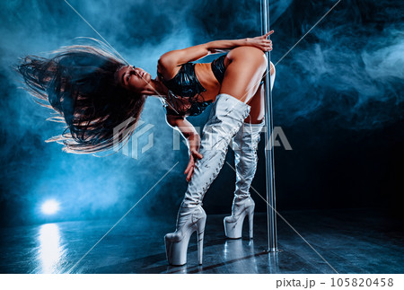 Young woman pole dancing on dark background with blue smoke 105820458