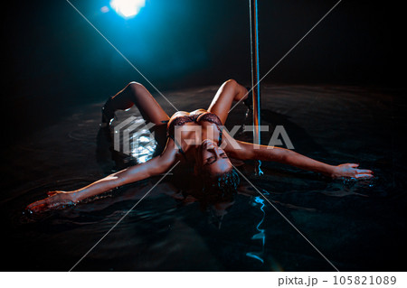 Young woman pole dancer posing in water with blue light Young woman pole dancer posing in water with blue light 105821089
