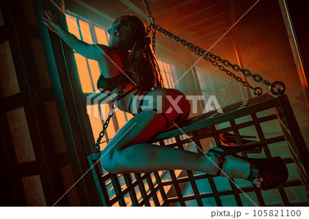 Young woman dancer posing in hall with metallic cage 105821100