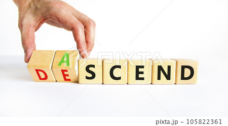 Ascend or descend symbol. Concept words Ascend and Descend on wooden cubes. Beautiful white table white background. Businessman hand. Business ascend or descend concept. Copy space. 105822361