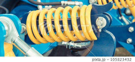 Hard spring made of steel. Part and detail of blue industrial or agricultural machine 105823432