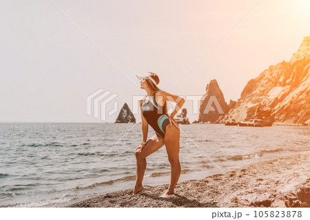 Woman beach vacation photo. A happy tourist in a blue bikini enjoying the scenic view of the sea and volcanic mountains while taking pictures to capture the memories of her travel adventure. 105823878