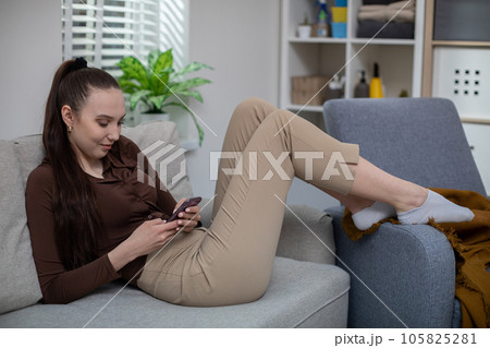Young girl relaxes on couch with cell phone Young girl relaxes on couch with cell phone 105825281