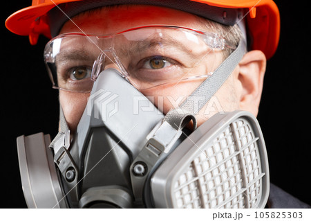 A man wearing a helmet, respirator and goggles on a black background 105825303