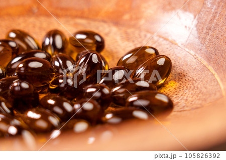 Herbal capsules from medicinal cannabis plant. CBD pills in wooden bowl. Cannabidiol herb treatment. Macro shot 105826392