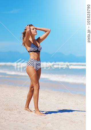 Ocean air and salty hair. Shot of a young woman enjoying a summers day at the beach. 105828790