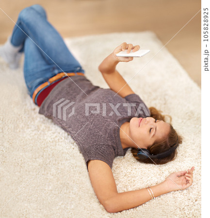 The perfect way to relax. a young woman listening to music while relaxing at home. 105828925