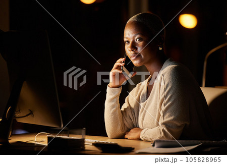 Focused on getting done and dusted with her deadline. Shot of a young businesswoman talking on a cellphone while working on a computer in an office at night. 105828965
