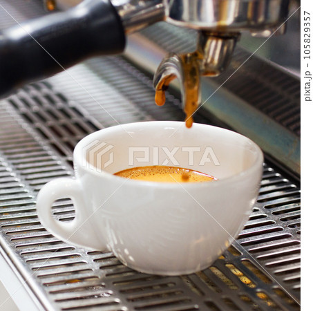 Coffee machine, restaurant and espresso or hot drink in a cup at a small business on counter top. Kitchen, cafe and pouring latte or caffeine at shop with preparation with electrical appliance. Coffee machine, restaurant and espresso or hot drink in a cup at a small business on counter top. Kitchen, cafe and pouring latte or caffeine at shop with preparation with electrical appliance. 105829357