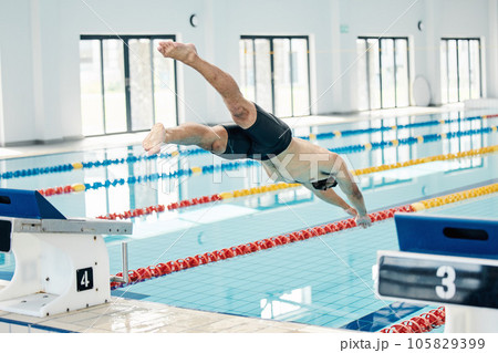 Sports, swimming pool and man diving in water for training, exercise and workout for competition. Fitness, wellness and professional male athlete in action for dive, jump and race from diving board Sports, swimming pool and man diving in water for training, exercise and workout for competition. Fitness, wellness and professional male athlete in action for dive, jump and race from diving board 105829399