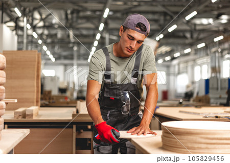 Young carpenter making wood furniture while working in joinery Young carpenter making wood furniture while working in joinery 105829456