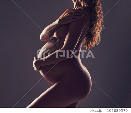 Body of pregnant woman, naked in studio and hand on stomach, aesthetic dark background at maternity reveal. Creative pregnancy photoshoot, art and nude mother holding belly with health and wellness. 105829570