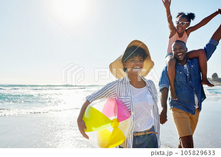 Black family, beach ball and summer at the beach while happy and walking together holding hands. Man, woman and a girl child excited about holiday at the ocean with freedom, happiness and fun outdoor Black family, beach ball and summer at the beach while happy and walking together holding hands. Man, woman and a girl child excited about holiday at the ocean with freedom, happiness and fun outdoor 105829633