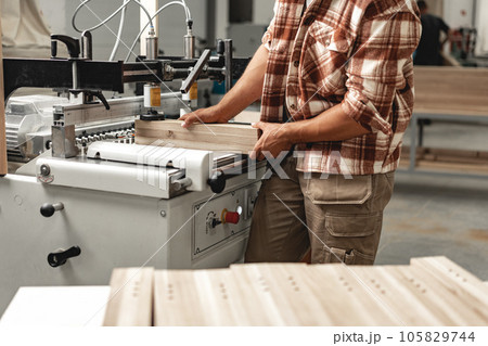Close-up of carpenter's hands working with wood piece in a workshop 105829744