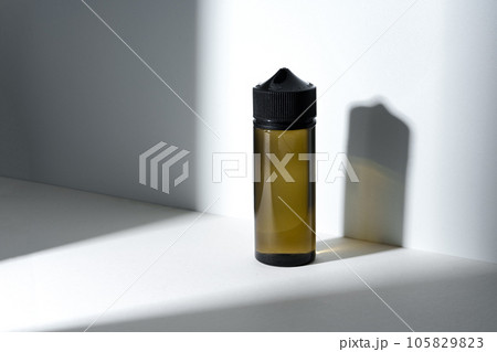 Dropper bottle with vape liquid on white background in the sunlight with shadows Dropper bottle with vape liquid on white background in the sunlight with shadows 105829823