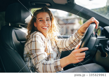 Happy smiling woman inside a car driving in the street Happy smiling woman inside a car driving in the street 105829961