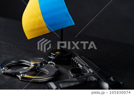 Ukrainian flag and handcuffs on black background, concept of crime and justice in the country 105830074