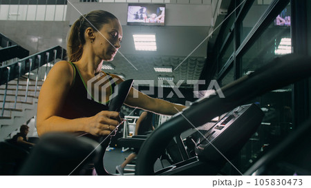 Fit Athletic Woman Exercising on an Elliptical Machine. Muscular Women Activity Training in Modern Gym. Workout in an Elliptic Walking Trainer. 105830473